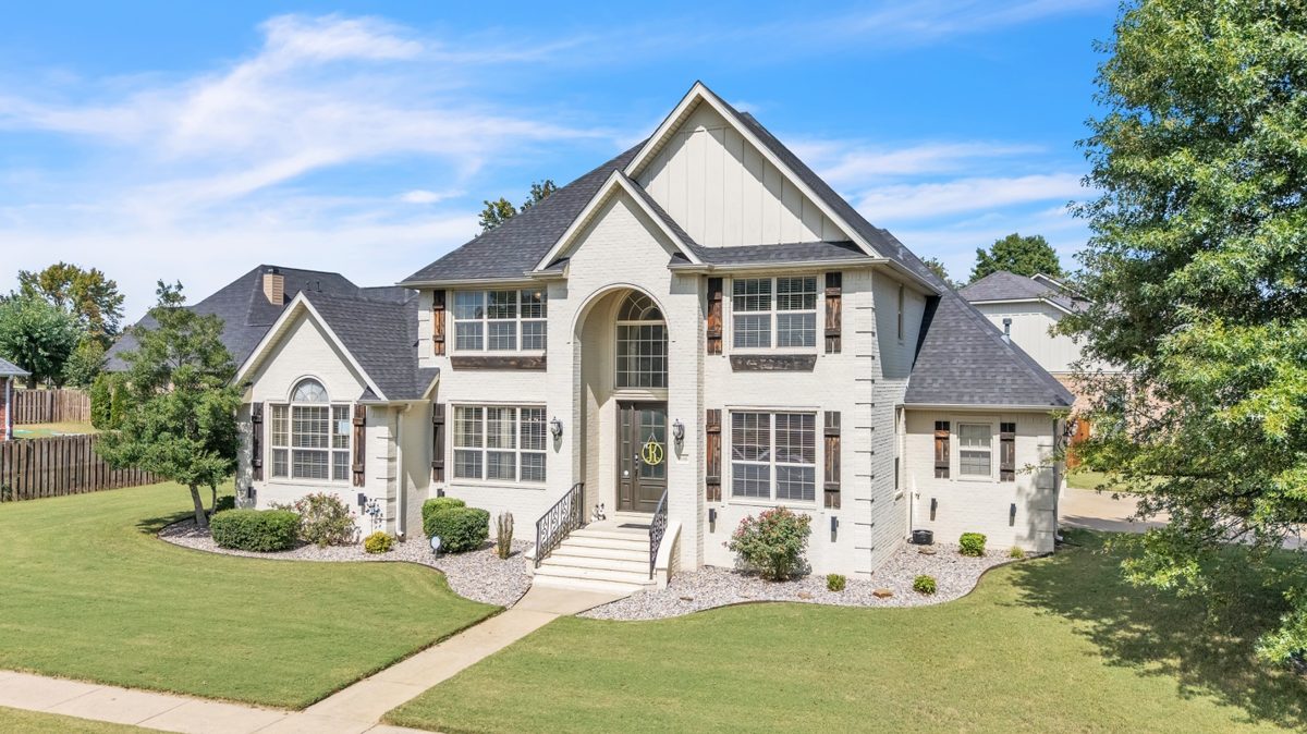Elevated aerial view of a two-story brick and stone home with manicured front lawn — drone real estate photography by Oakmont Visuals
