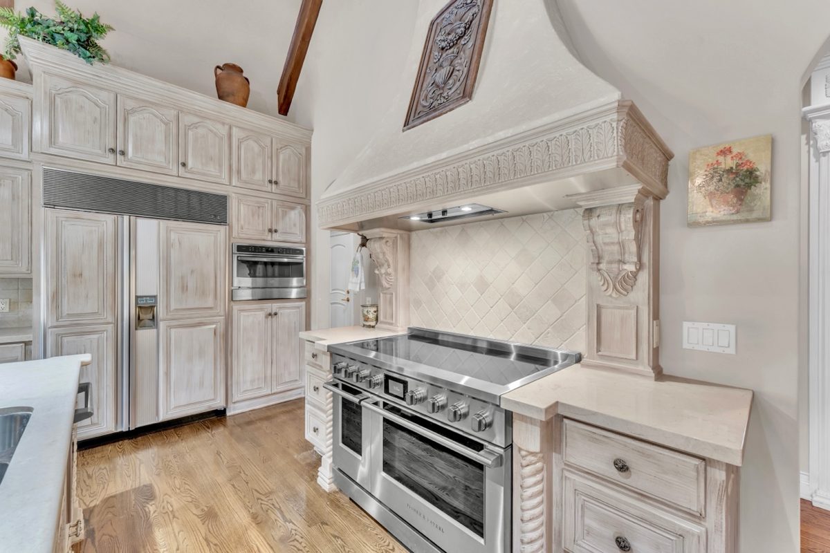 Custom kitchen with professional range, carved wood hood, and tile backsplash — real estate interior photography by Oakmont Visuals