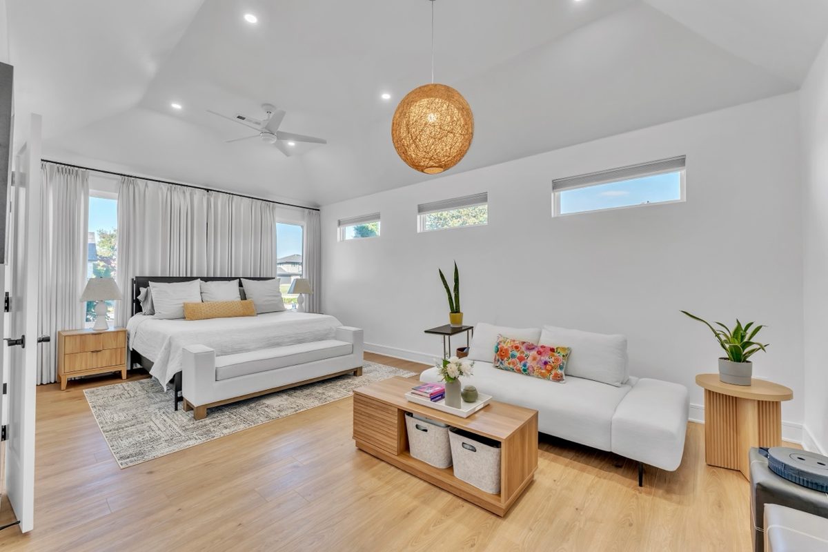 Bright primary bedroom with seating area, hardwood floors, and natural light — real estate interior photography by Oakmont Visuals