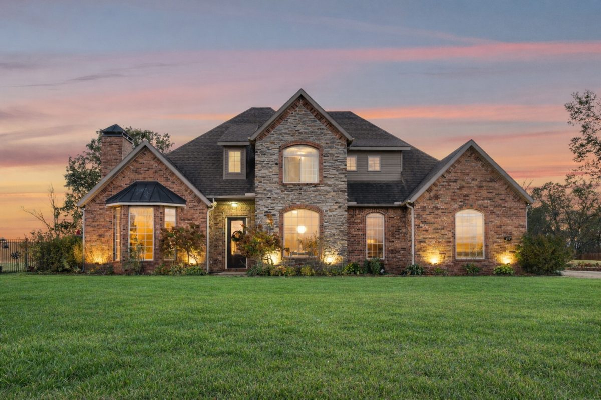 Brick and stone home exterior photographed at twilight with warm interior lighting — twilight real estate photography by Oakmont Visuals